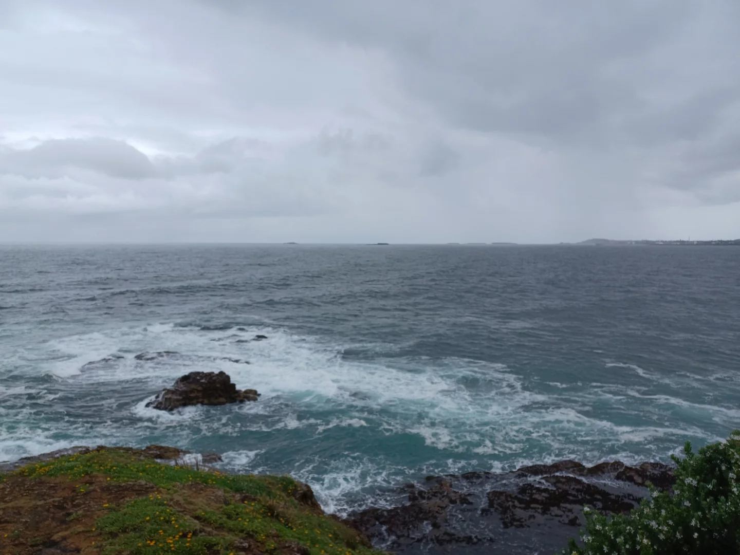 Surf breaking around the rocky Illawarra shoreline, with islands on the horizon